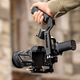 The DJI RS 3 Mini stabilizer being held 'briefcase' style with a handle above the stabilizing mechanism.